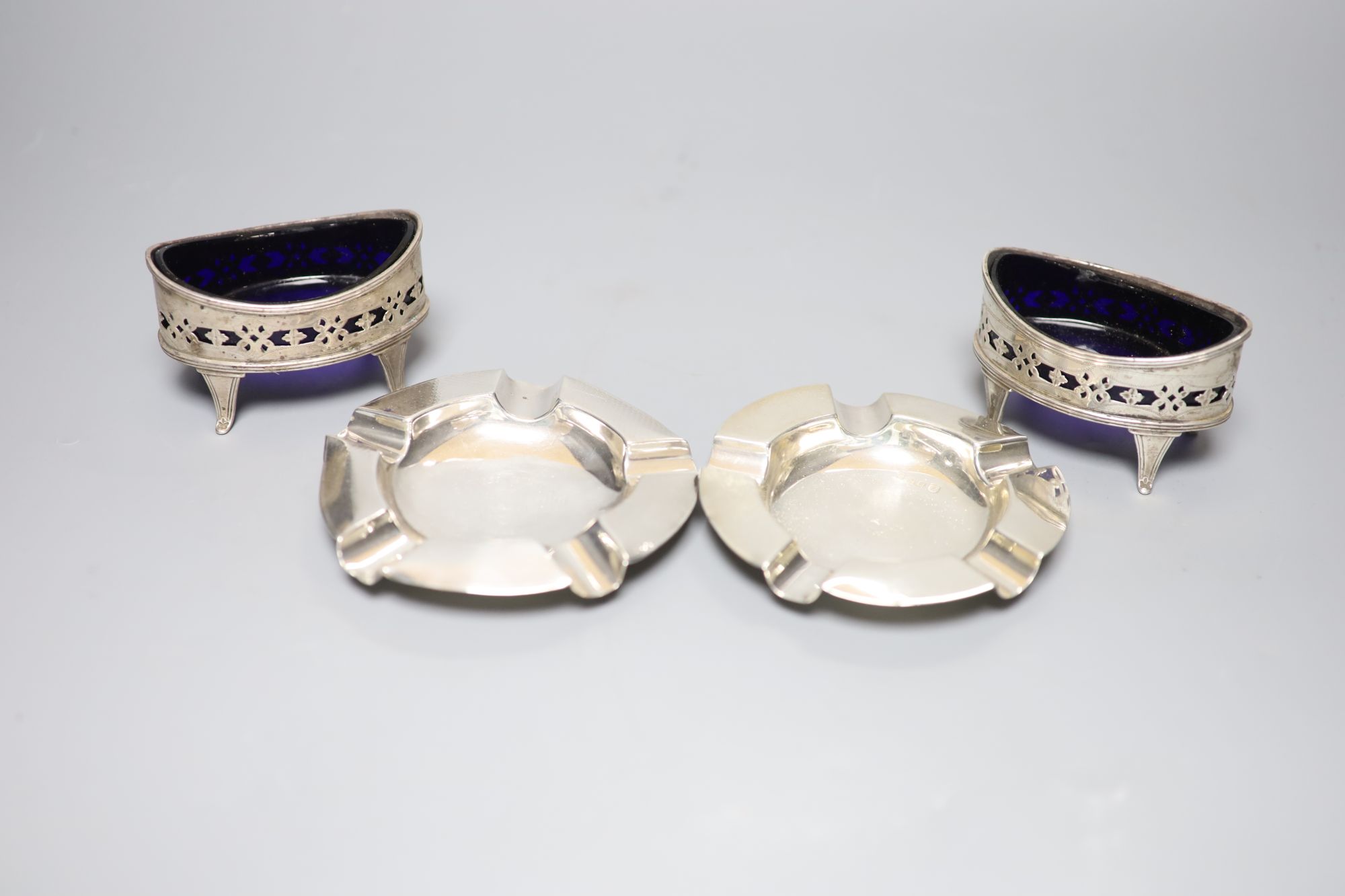 A pair of Victorian pierced silver navette shaped salts, London, 1896 and two later silver ashtrays.   ashtrays